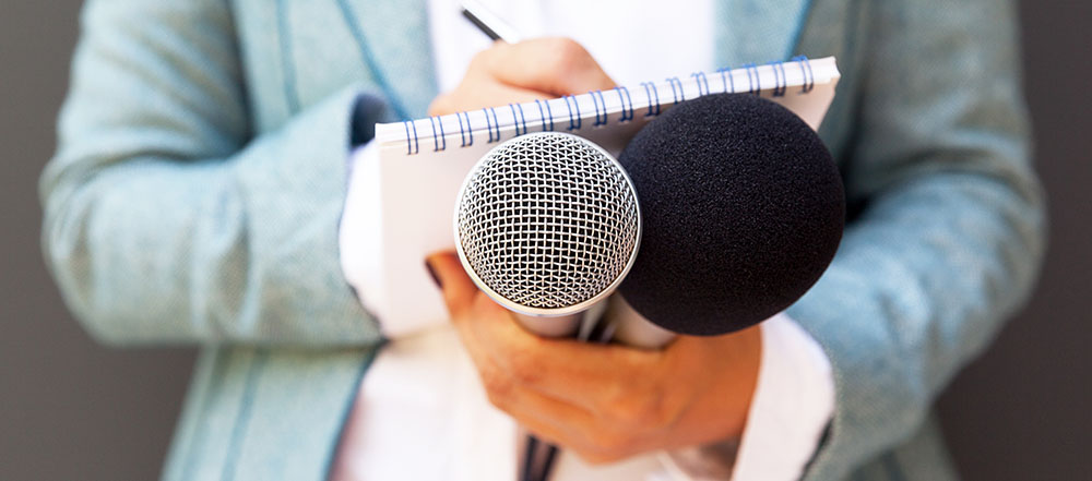 Someone holding two mics and making notes