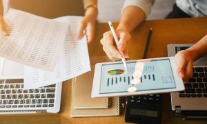 lose up group of businessman use stylus pen for explaining dashboard about company's profit monthly on tablet and businesswoman holding report paper for collaborate work at meeting event , business finance concept