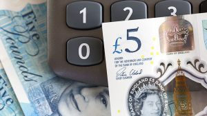 A 5 pound note resting on a calculator