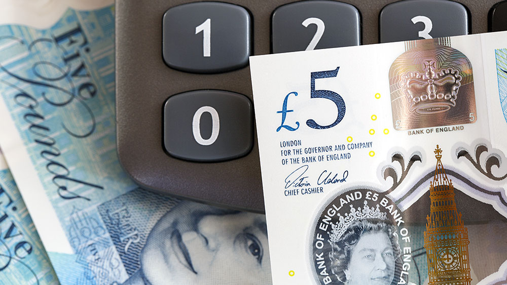 A 5 pound note resting on a calculator
