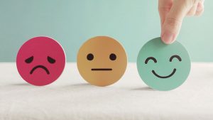 A red unhappy face, a yellow frowning face and and a smiling green face, the green face is being picked up