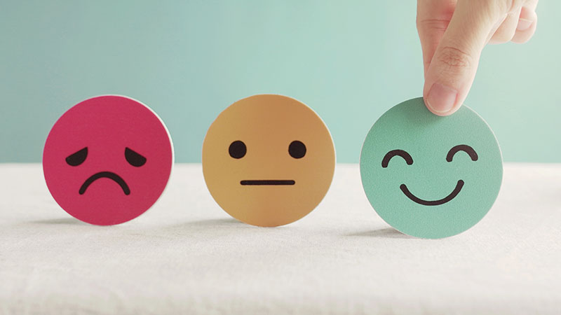 A red unhappy face, a yellow frowning face and and a smiling green face, the green face is being picked up